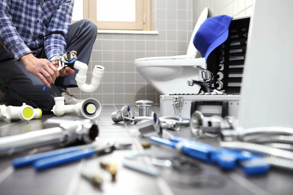 plumber with tools fixing a toilet