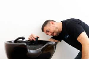 A plumber at contemporary plumbing checking the sink
