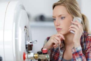 A woman speaks to plumber on a mobile phone.